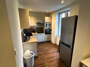 cocina con armarios blancos y nevera negra en # Le 3 # Joli appartement T3 Mulhouse centre, Neuf, calme et tout équipé en Mulhouse