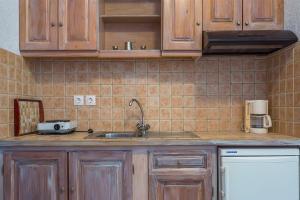 cocina con armarios de madera, fregadero y nevera en Irida Apartments, en Stafylos