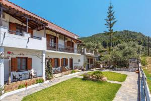 una gran casa blanca con un jardín delante de ella en Irida Apartments, en Stafylos