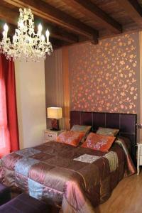 ein Schlafzimmer mit einem großen Bett und einem Kronleuchter in der Unterkunft Casa Rural El Rosal del Pozo, a 5 minutos de Puy du Fou in Argés
