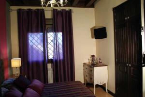 a bedroom with purple curtains and a bed and a dresser at El Rosal del Pozo in Argés