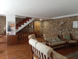 a living room with chairs and a stone wall at casa na aldeia - entre Fundão e Covilhã in Pêro Viseu