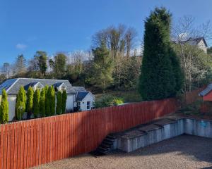 a red fence with trees and houses in the background at Ardlinnhe Bed & Breakfast in Fort William