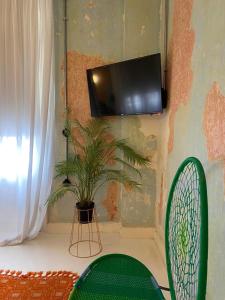 a tv on a wall with a plant and a chair at Trilogy Experimental in Thessaloniki