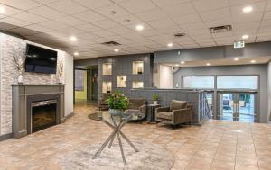 a lobby with a fireplace and a table and chairs at Comfort Suites Kingston Central in Kingston