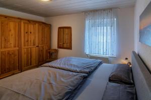 - une chambre avec un lit, des armoires en bois et une fenêtre dans l'établissement Strandflieder, à Dornumersiel