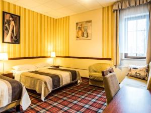 a hotel room with two beds and a chair at Hotel Stara Garbarnia in Wrocław