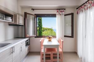 a kitchen with a small table and a window at Theoxenia Apartments in Ormos Panagias