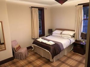 a bedroom with a bed and a chair and windows at The Brunstane Lodge in Strathpeffer
