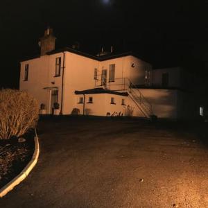 un grande edificio bianco di notte con un cielo scuro di The Brunstane Lodge a Strathpeffer