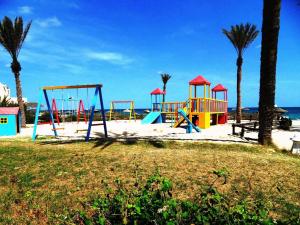 einen Spielplatz am Strand mit Palmen und dem Meer in der Unterkunft Zita Beach Resort in Zarzis