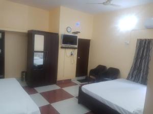 a hotel room with two beds and a tv at SM Guest House in Lucknow