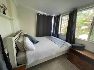 a bedroom with a bed and two windows at Little Ray on Sunshine. Hamptons style beachhouse in Woorim