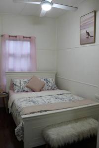 a bedroom with a bed with a ceiling fan at Little Ray on Sunshine. Hamptons style beachhouse in Woorim