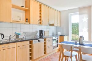 una cocina con armarios de madera, mesa y sillas en Ferienwohnung Möwe, en Lanken