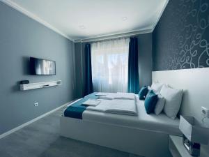 a bedroom with a bed with blue walls and a window at Thermal Family in Makó