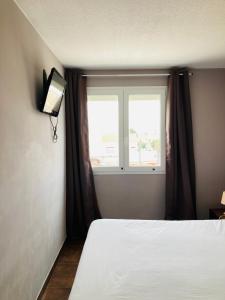 a bedroom with a bed and a window at Hotel le Provençal in Narbonne-Plage