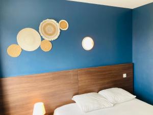 1 dormitorio con una pared azul, 1 cama y 2 luces en Hotel le Provençal, en Narbonne-Plage
