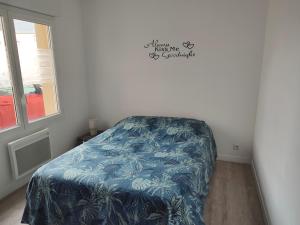ein Schlafzimmer mit einem Bett mit einer blauen Decke in der Unterkunft Le pont T3 étoilé avec jacuzzi in Saint-Méloir-des-Ondes