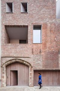 a woman walking past a brick building with two garage doors at Great in Ghent