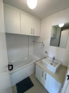 a white bathroom with a sink and a bath tub at Cozumel 311 in Umdloti