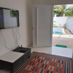 a living room with a tv and a rug at Casa Vitória em barra de jacuipe in Campos