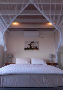 a bedroom with a bed with a white canopy at Coral Tree Surf Cottage - Tofinho, Tofo in Praia do Tofo