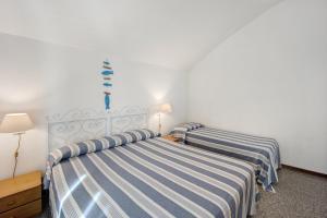 dwa łóżka w pokoju hotelowym z prześcieradłami w paski w obiekcie Appartamento Orizzonte 9 A w mieście Diano Marina