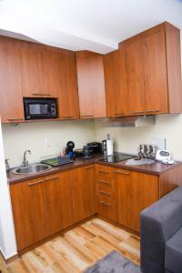 a kitchen with wooden cabinets and a sink and a microwave at Apartman Lily in Brzeće