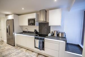una cocina con armarios blancos y electrodomésticos de acero inoxidable en The Sandringham Suite, en Plymouth