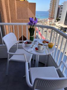 una mesa y sillas en un balcón con una mesa y flores en Hotel Golden, en Benidorm