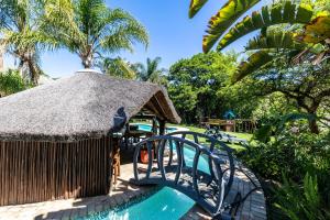 a resort with a swimming pool with a thatch roof at Fish Eagle Manor in East London