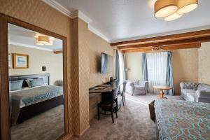 a hotel room with a bed and a desk and a mirror at Atlas Posthotel in Garmisch-Partenkirchen