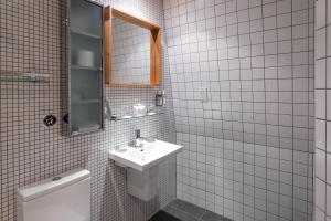 a white tiled bathroom with a sink and a toilet at Hotel Hebrides in Tarbert