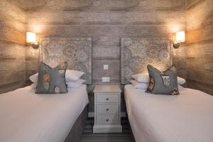 two twin beds in a room with wooden walls at Hotel Hebrides in Tarbert