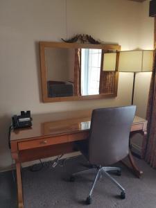 Habitación con escritorio con espejo y silla. en Owen Sound Inn, en Owen Sound