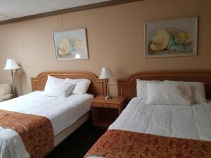 a hotel room with two beds and paintings on the wall at Owen Sound Inn in Owen Sound