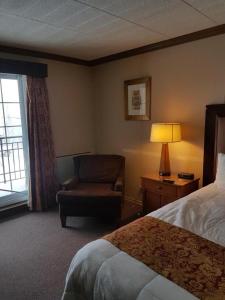 a hotel room with a bed and a chair and a window at Owen Sound Inn in Owen Sound