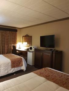a hotel room with two beds and a desk with a television at Owen Sound Inn in Owen Sound