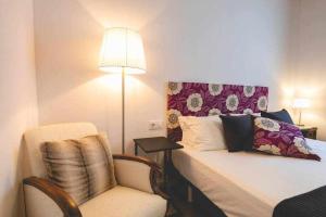 a bedroom with a bed and a chair and a lamp at Newly renovated room w Pool & BikeParking in Girona +31 photos