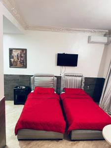 um quarto com 2 camas com lençóis vermelhos e uma televisão de ecrã plano em SINGAPOUR MAROC em Casablanca