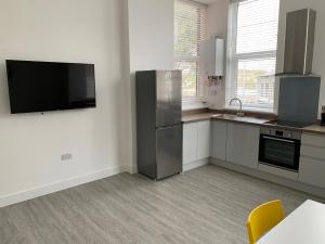 a kitchen with a refrigerator and a tv on the wall at Kings Cross by Pureserviced in Plymouth