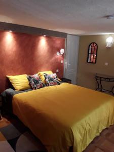 een slaapkamer met een groot bed met gele lakens en kussens bij Gite les Cigales in Châteauvieux