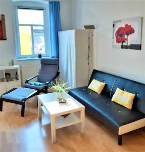 ein Wohnzimmer mit einem schwarzen Sofa und einem Tisch in der Unterkunft Citywohnung Altstadt in Halle an der Saale