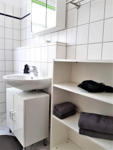 ein weißes Badezimmer mit einem Waschbecken und einem Spiegel in der Unterkunft Citywohnung Altstadt in Halle an der Saale