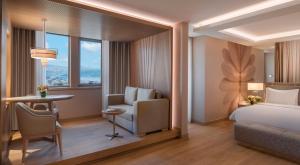 a room with a bed, chair, desk and a window at Mövenpick Hotel Istanbul Bosphorus in Istanbul