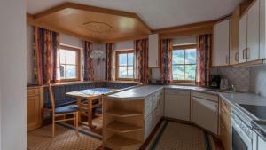 a kitchen with white cabinets and a table and windows at Außermoos-Zuhaus in Alpbach