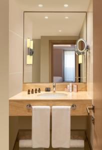 a bathroom with a sink, mirror, and towel rack at Mövenpick Hotel Istanbul Bosphorus in Istanbul