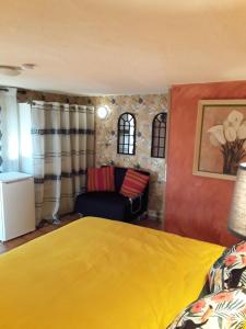 a bedroom with a yellow bed and a couch at Gite les Cigales in Châteauvieux