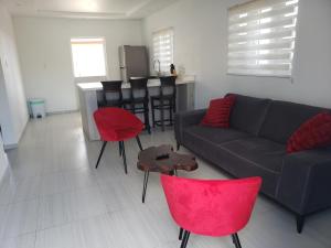 een woonkamer met een bank en rode stoelen bij CG Apartment - Flamboyan in Willemstad